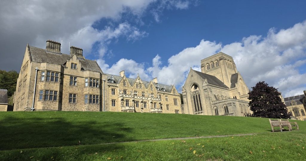 Ampleforth Abbey church and monastery buildings above a green lawn on a sunny day